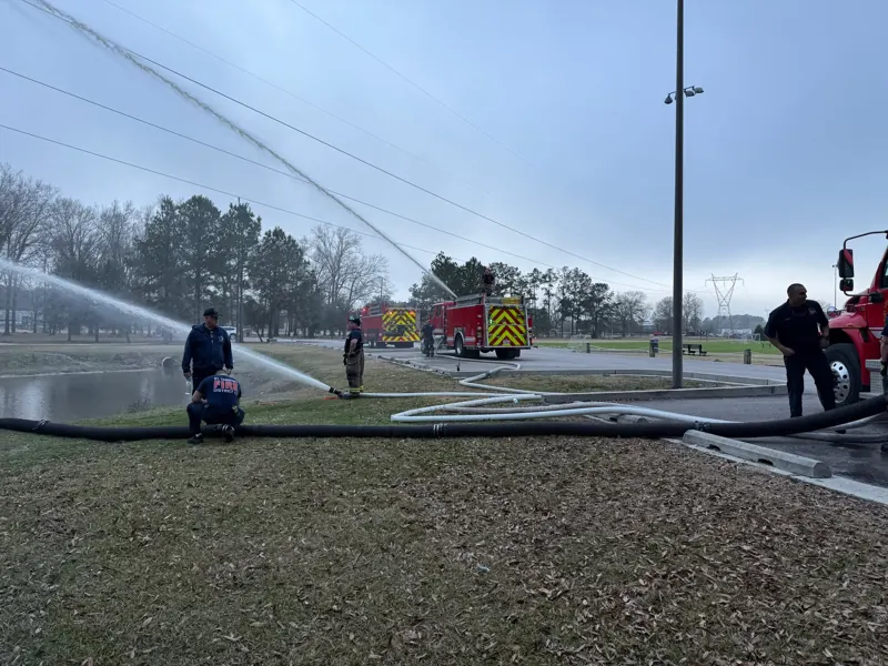 Crews flowing hose streams across a field
