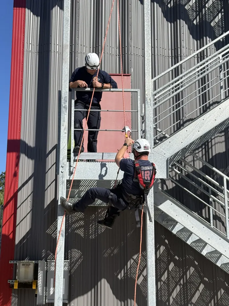 Firefighters on ropes at the top of the red training tower