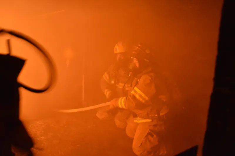 Firefighter advancing a hoseline through heavy smoke